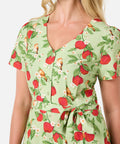 Woman wearing a green dress with red apple pattern on a white background