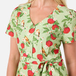 Woman wearing a green dress with red apple pattern on a white background
