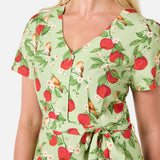 Woman wearing a green dress with red apple pattern on a white background