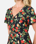 Woman wearing a dress with a floral and apple pattern