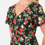 Woman wearing a dress with a floral and apple pattern