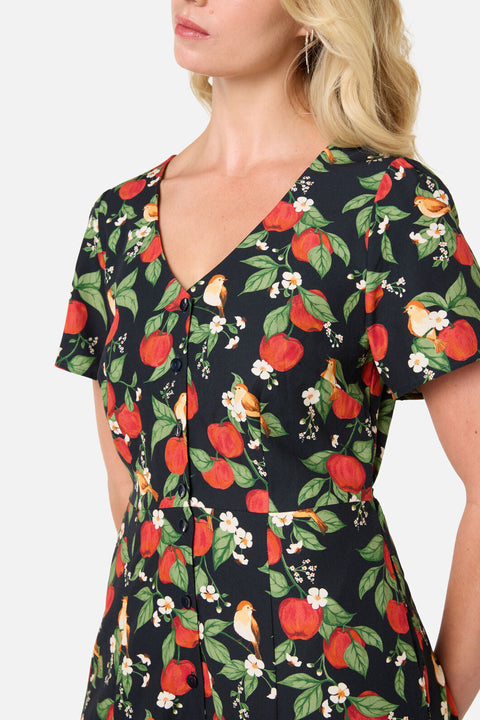 Woman wearing a dress with a floral and apple pattern