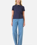 Woman wearing a navy shirt and light blue jeans on a white background