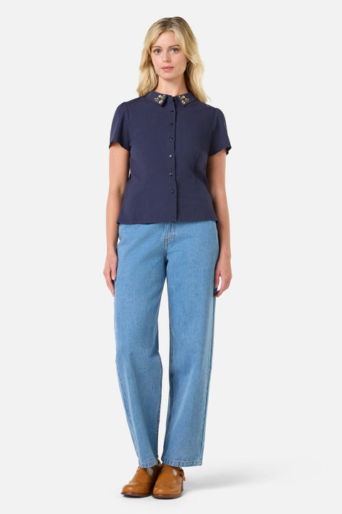 Woman wearing a navy shirt and light blue jeans on a white background