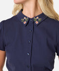 Navy blue blouse with floral embroidery on collar worn by a woman