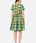 Back view of woman wearing a green and yellow checkered dress on a white background