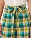 Green and yellow plaid pants with a tie waist worn by a woman.