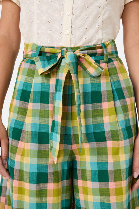 Green and yellow plaid pants with a tie waist worn by a woman.