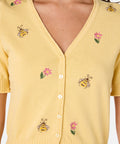 Yellow cardigan with bee and flower embroidery on a plain background