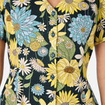 Close-up of a floral dress with yellow, blue, and white flowers on a dark background.