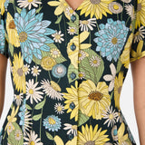 Close-up of a floral dress with yellow, blue, and white flowers on a dark background.