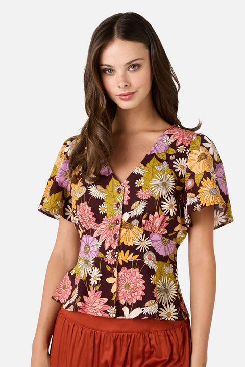 Woman wearing a short sleeve floral blouse with a plain background