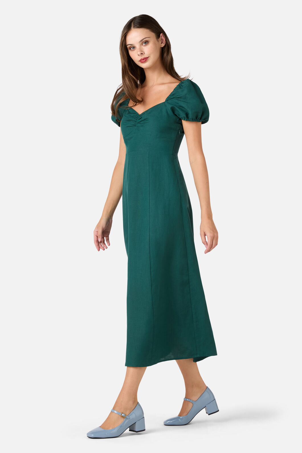 Woman wearing a green dress with puff sleeves on a white background