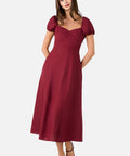 Woman wearing a burgundy dress with puff sleeves on a white background