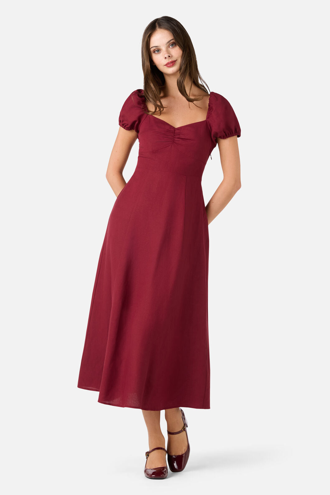 Woman wearing a burgundy dress with puff sleeves on a white background
