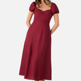 Woman wearing a burgundy dress with puff sleeves on a white background