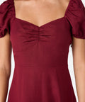 Maroon dress with puff sleeves on a plain background