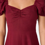 Maroon dress with puff sleeves on a plain background