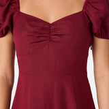 Maroon dress with puff sleeves on a plain background