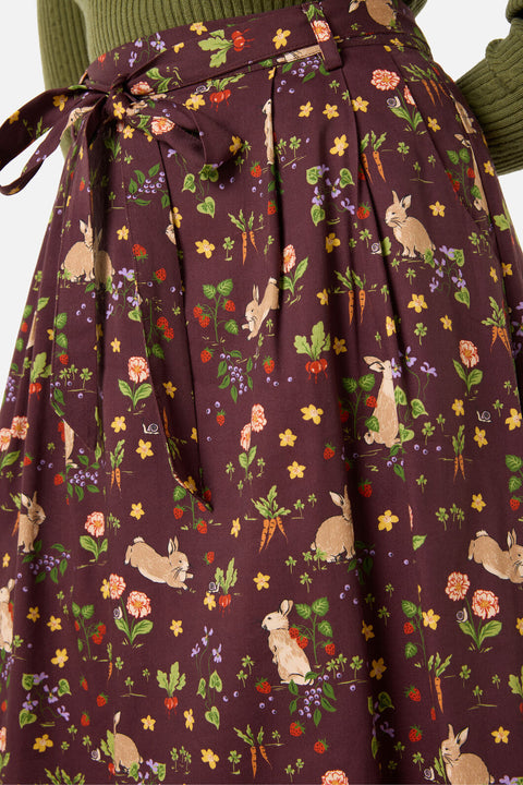 Woman wearing a skirt with rabbit and floral pattern on a brown background