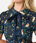 Woman wearing a navy blue blouse with bow, rabbits and colorful floral pattern