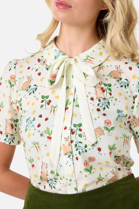 Woman wearing a floral blouse with a tie collar on a white background