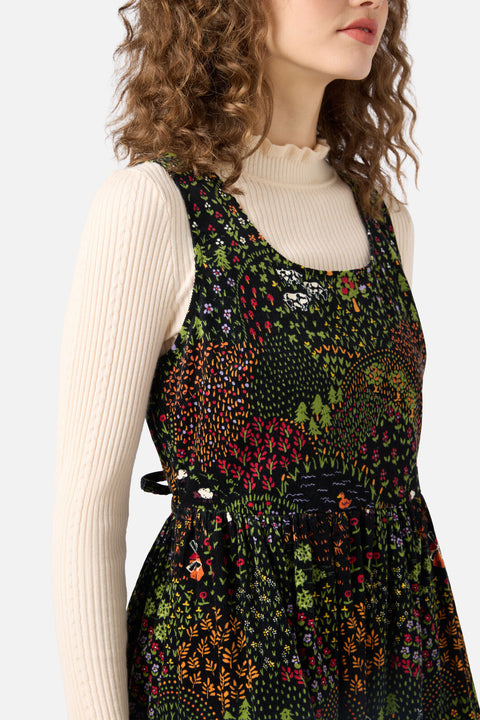 Woman wearing a floral dress over a beige sweater on a white background