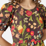 Woman wearing a brown autumn floral dress with short sleeves and a round neckline