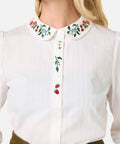 White shirt with floral collar and embroidery on a plain background