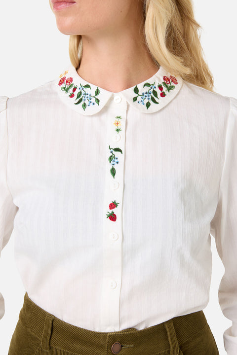 White shirt with floral collar and embroidery on a plain background