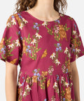 Woman wearing a magenta dress with floral and animal print on a white background