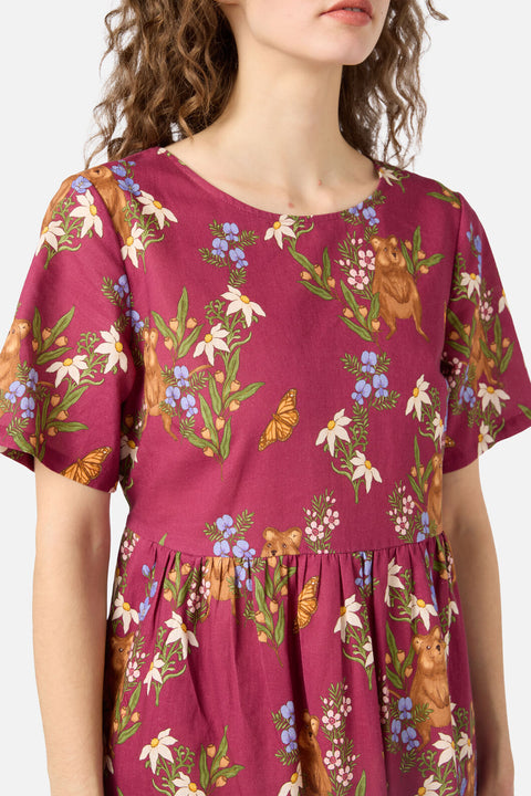 Woman wearing a magenta dress with floral and animal print on a white background
