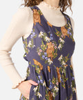 Woman wearing a floral and animal print dress over a beige long-sleeve shirt.