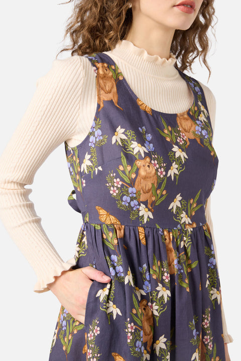 Woman wearing a floral and animal print dress over a beige long-sleeve shirt.
