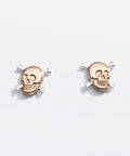 Pair of gold skull earrings on a light gray background