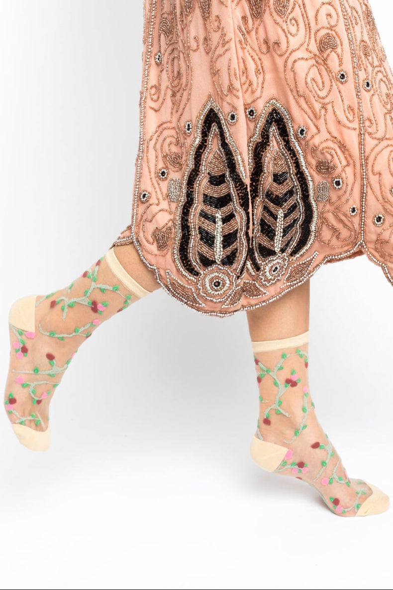 Traditional embroidered garment with floral-patterned socks on a white background