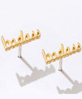 Gold 'badass' earrings on a white background