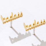 Gold 'badass' earrings on a white background