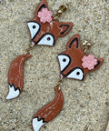 Fox-shaped earrings with floral details on a textured surface