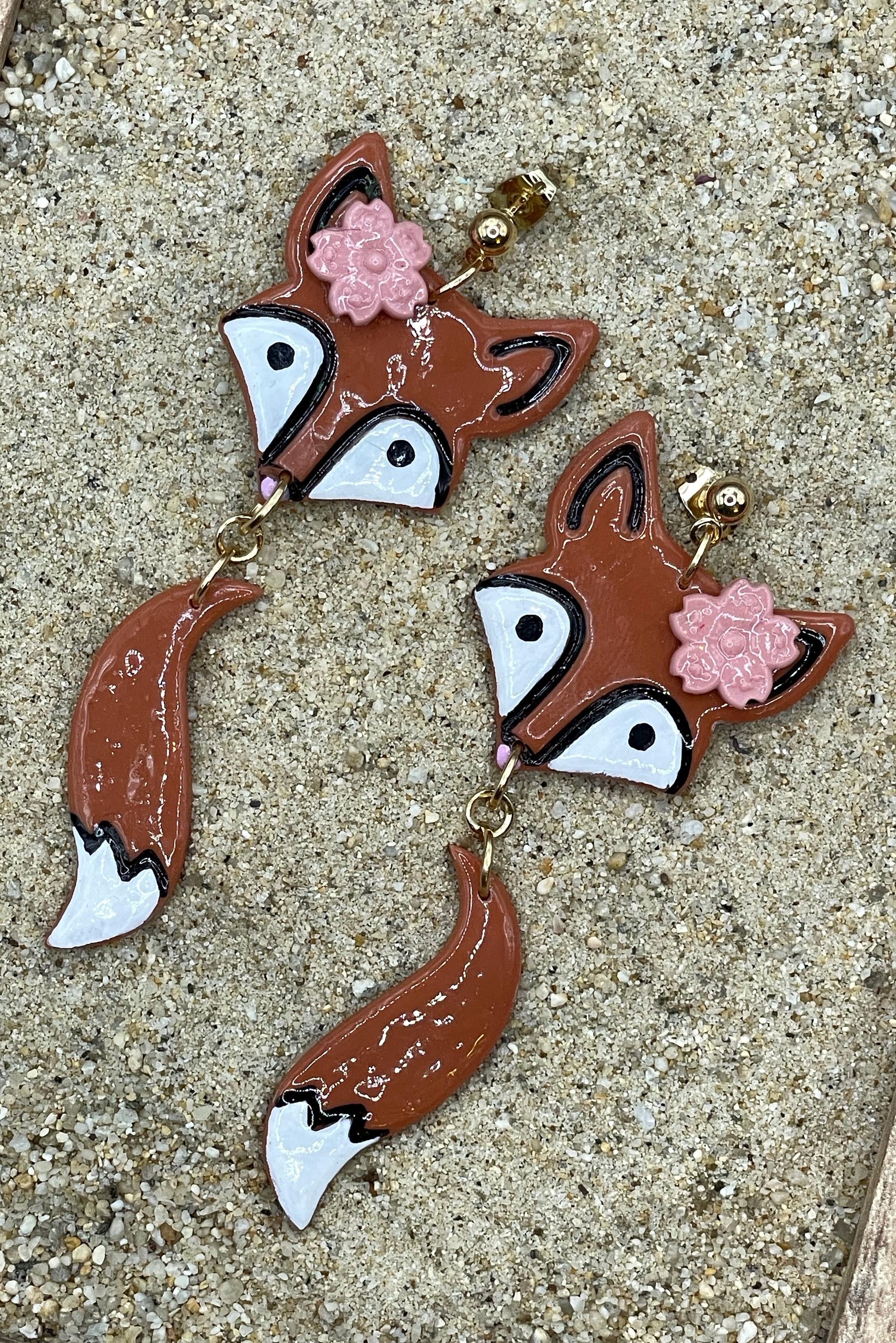 Fox-shaped earrings with floral details on a textured surface