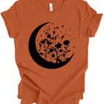An orange short-sleeve t-shirt with a black graphic of a crescent moon, wildflowers, and stars on the front, displayed on a clean white background.