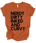 An orange short-sleeve t-shirt with the phrase 'NERDY DIRTY INKED AND CURVY' printed in bold black capital letters on the front, shown against a plain white background.