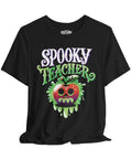 A black short-sleeve t-shirt with a 'Spooky Teacher' graphic on the front, featuring a dripping green slime apple with a skull face. The brand name 'SELF CARE' is printed inside the collar.