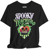 A black short-sleeve t-shirt with a 'Spooky Teacher' graphic on the front, featuring a dripping green slime apple with a skull face. The brand name 'SELF CARE' is printed inside the collar.